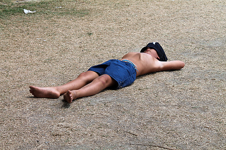 boy sleeping on soil covering his face during daytime thumbnail