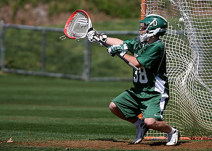 player in green jersey and shorts holding lacrosse stick thumbnail