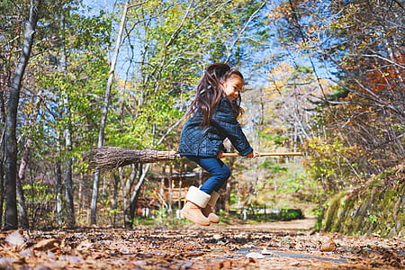 girl in blue coat riding broom jumpshot during daytime thumbnail