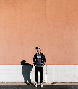man standing near orange and white wall during daytime thumbnail