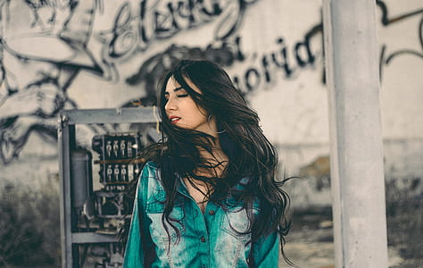 woman looking to her right standing in front of wall with grafitti thumbnail