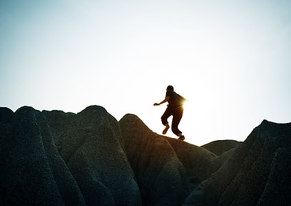 silhouette of woman running on rock formation under white sky during daytime thumbnail