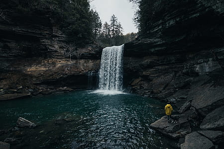 man standing on rock near waterfalls during daytime thumbnail