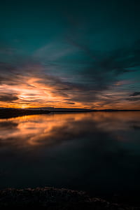 body of water under blue and orange sky during twilight thumbnail