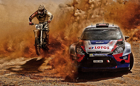person riding motocross dirt bike beside of white, blue, and red Ford Fiesta thumbnail