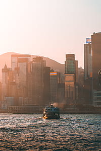 white and black boat on body of water near high buildings under white sky at daytime thumbnail