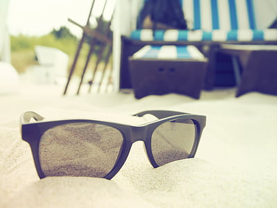 black sunglasses on white sand thumbnail