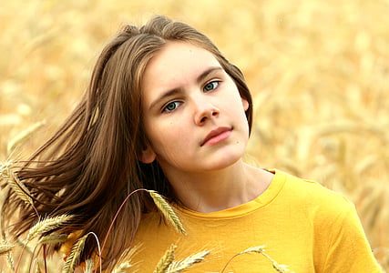 woman in yellow crew-neck shirt surrounded by yellow petaled flowers thumbnail