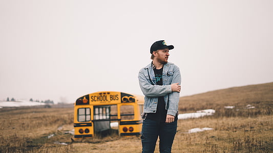 man standing near yellow school bus at daytime thumbnail