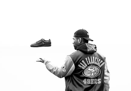 grayscale photo of man catching shoes thumbnail
