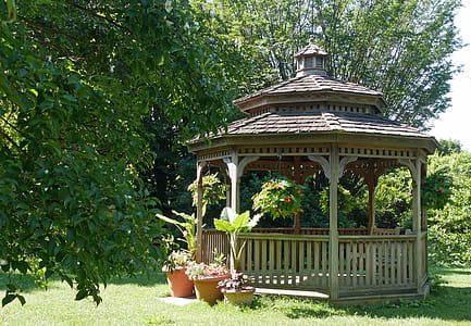 A small wooden gazebo in a backyard garden. thumbnail