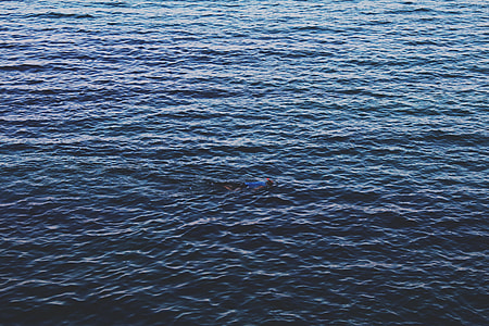 man wearing blue shirt floating on sea water during daytime thumbnail