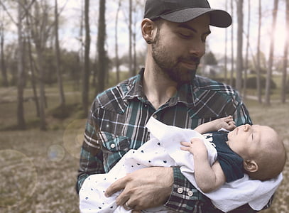smiling man carrying sleeping baby during daytime thumbnail