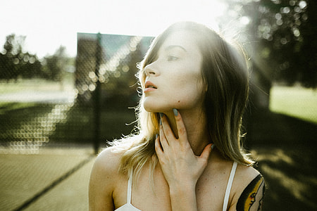 woman wearing white top looking rightwards with left hand on neck \ thumbnail