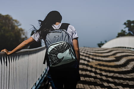 woman carrying gray backpack holding on bridge rails thumbnail