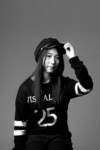woman in sweatshirt and hat grayscale photography thumbnail