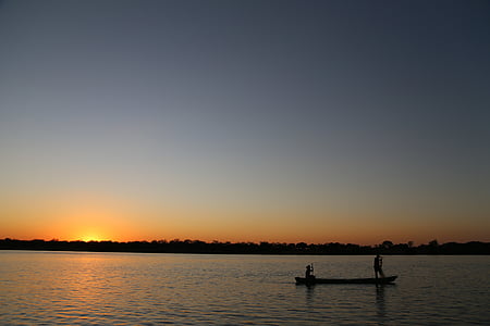two person riding boat on calm body of water during golden hour in silhouette photography thumbnail
