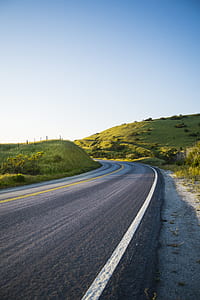 concrete road between green grass at daytime thumbnail