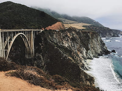photo of bridge by the rock mountain by the sea thumbnail
