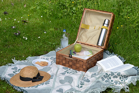 wicker brown picnic basket on grass with sun hat thumbnail