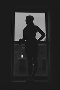 silhouette of woman standing on window thumbnail