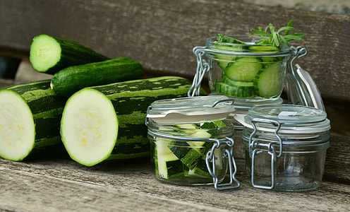 sliced green cucumber beside four clear glass jars on brown surface thumbnail