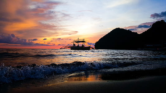 boat on water near mountain during sunset thumbnail