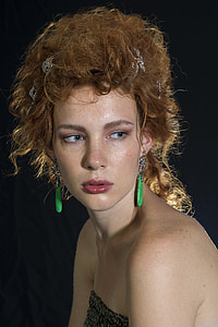 woman wearing jade earrings with blonde hair with black background photo thumbnail