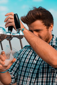 Man Holding Black Beer Tap Handle Pouring Beer on Clear Glass thumbnail