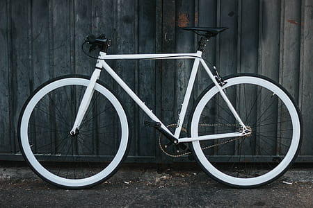white flat bar fix bike leaning on black fence thumbnail