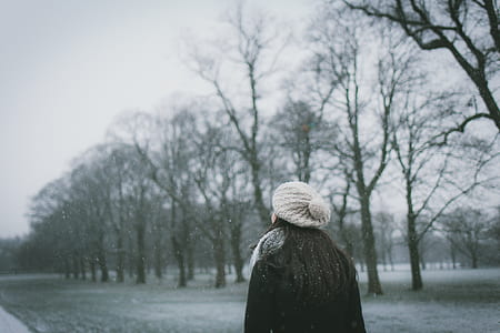 woman in black jacket walking under the snow thumbnail