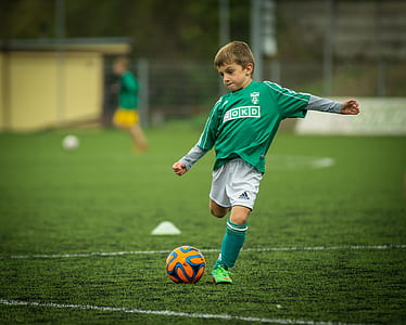 boy wearing green sweatshirt playing soccer thumbnail