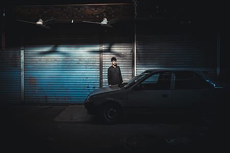man standing in front of gray car parked across the street thumbnail