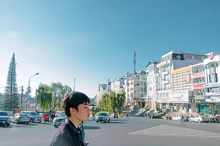Man Walking on Street Overlooking Building Under Blue Sky thumbnail
