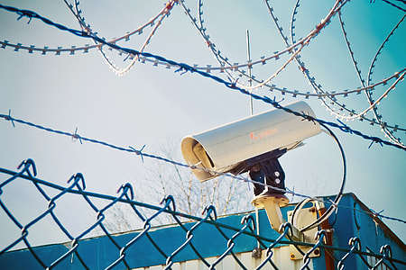 white security camera behind of wire fence during daytime thumbnail