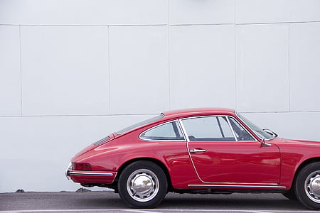 red coupe in front of white painted wall thumbnail