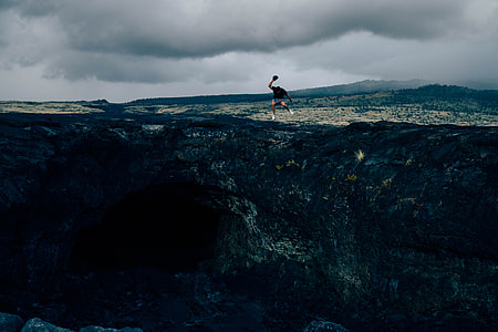 man in black shirt jumped on brown cliff thumbnail