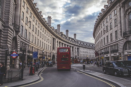 red double deck bus on road near concrete buildings during daytime thumbnail
