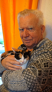 man holding cat beside orange curtain in room thumbnail