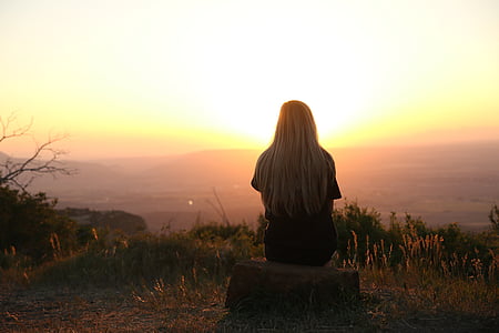 woman sitting on rock facing golden hour thumbnail
