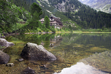 black wooden cabin near lake surrounded by mountains at daytime thumbnail