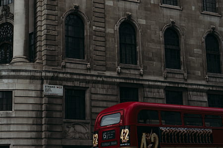 red bus passing building thumbnail