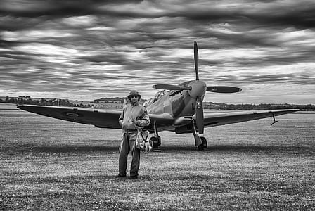 grayscale photography of man standing behind the plane thumbnail