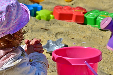 girl holding near pink plastic sand bucket during daytime thumbnail