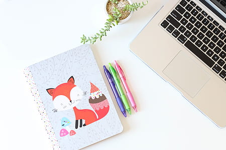 three assorted-color click pens beside grey laptop thumbnail