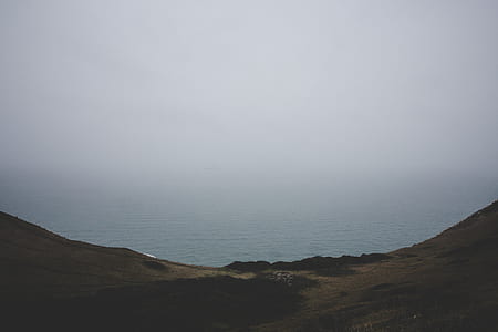 landscape photography of ocean near mountains thumbnail