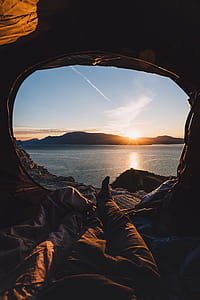person lying inside tent while watching at sunset thumbnail