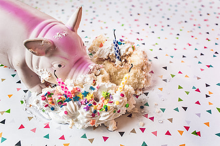 white and pink ceramic pig figurine near eaten cake thumbnail
