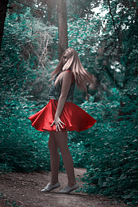 woman wearing green and red circle skirt surrounded by green leaf tree thumbnail