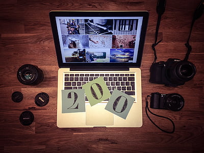 turned on Macbook beside black DSLR camera thumbnail